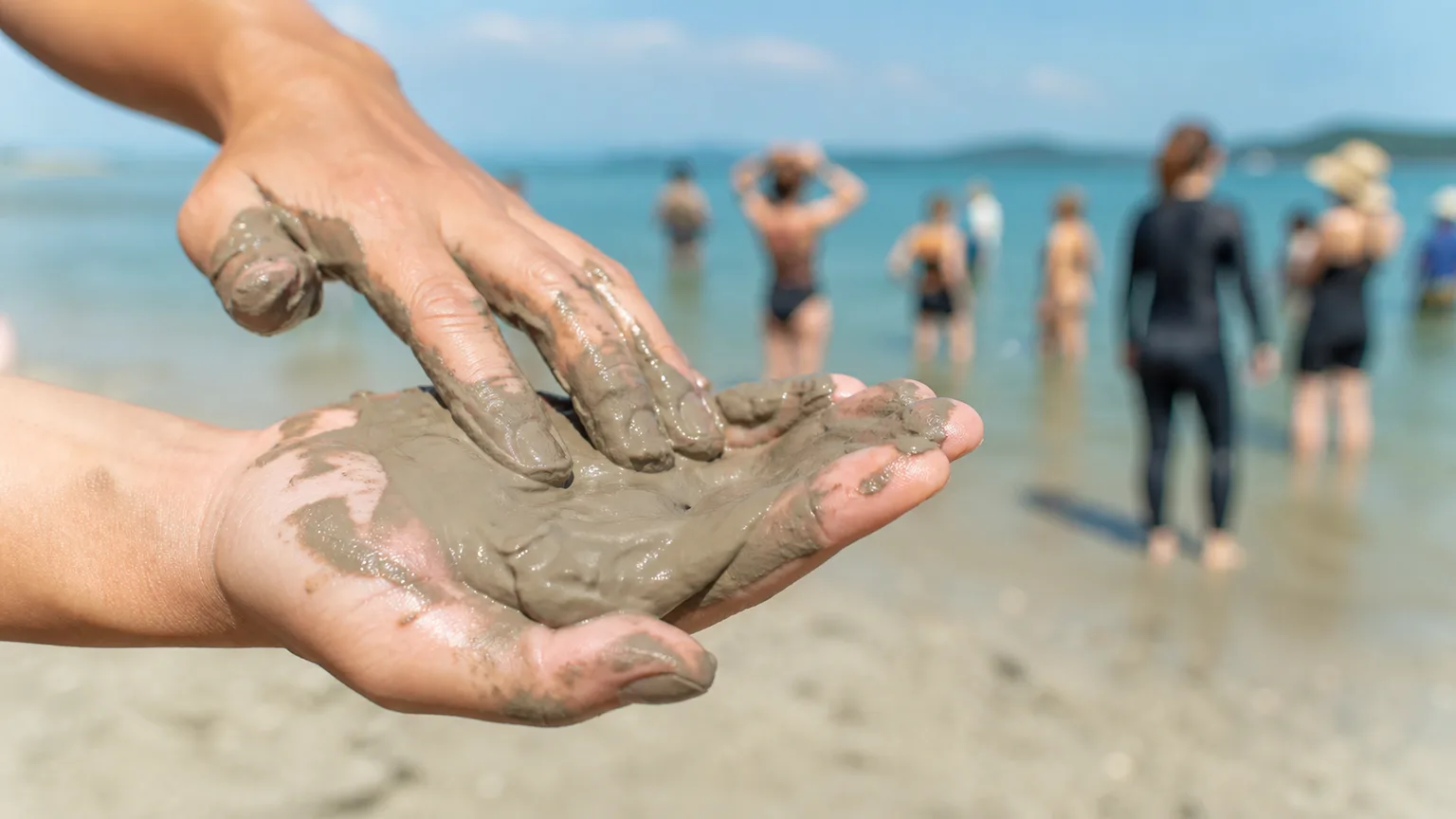 Natural mud held in an open hand beside the Korean coast.
