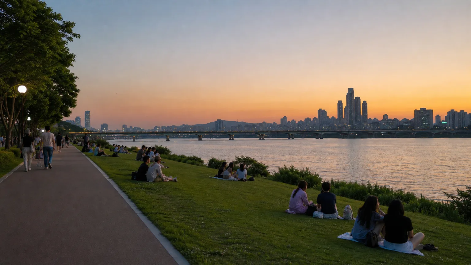 People relaxing beside the Seoul Han River at dusk